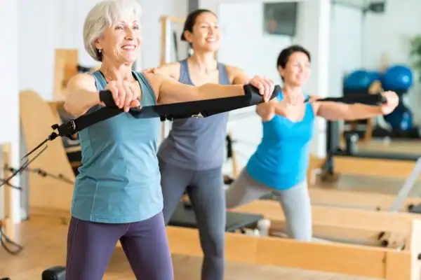 Toning Arms After 60: Empowering Womens Fitness Through Effective Weight Training 2 older woman doing weight training Bury St Edmunds and resistance in the gym to tone upper arms