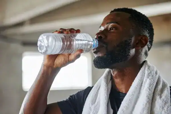Image of man drinking water to improve hydration Bury St Edmunds after work out.